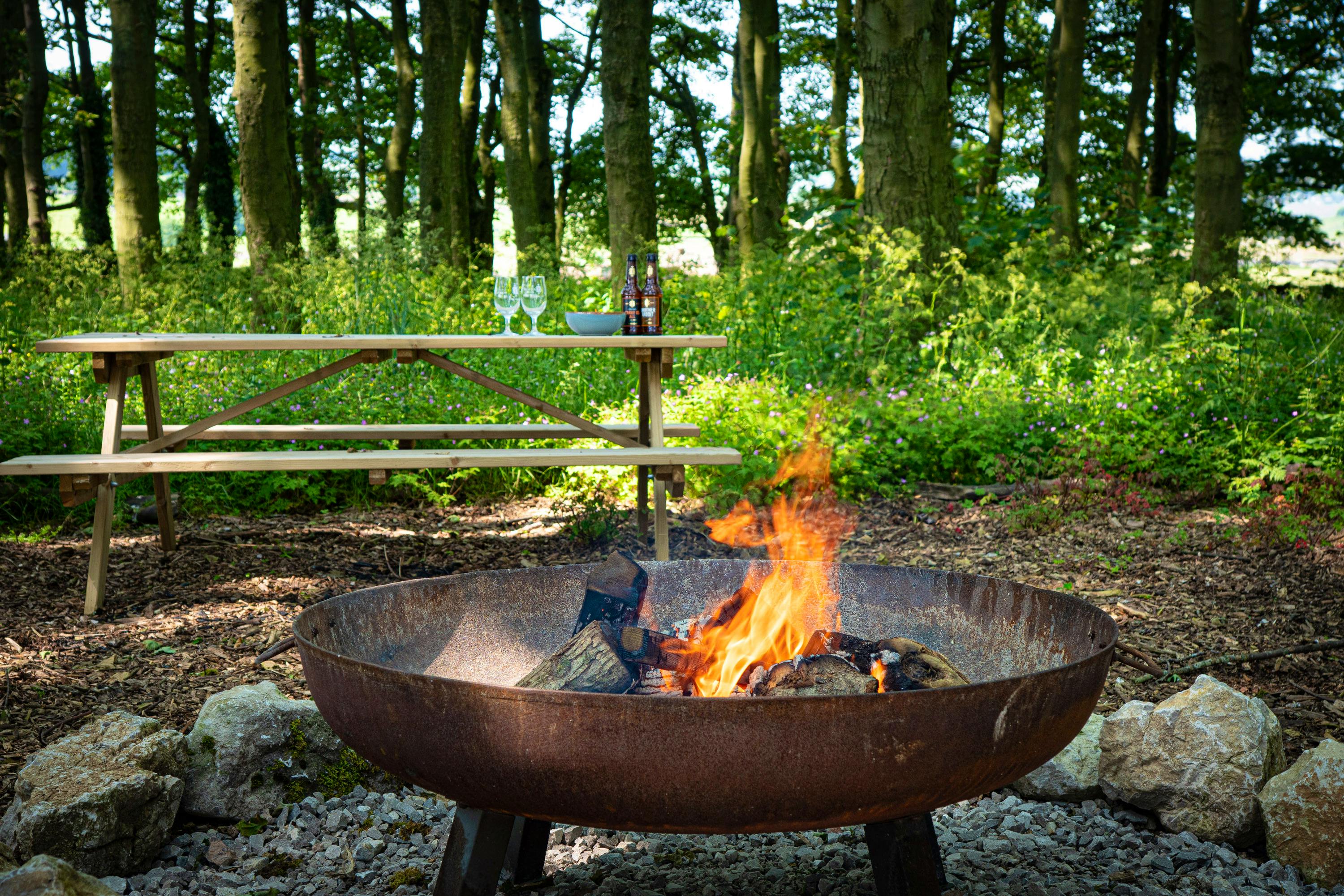 A fire-pit in the woods and other outdoor seating areas at Manor House Farm Cottages  