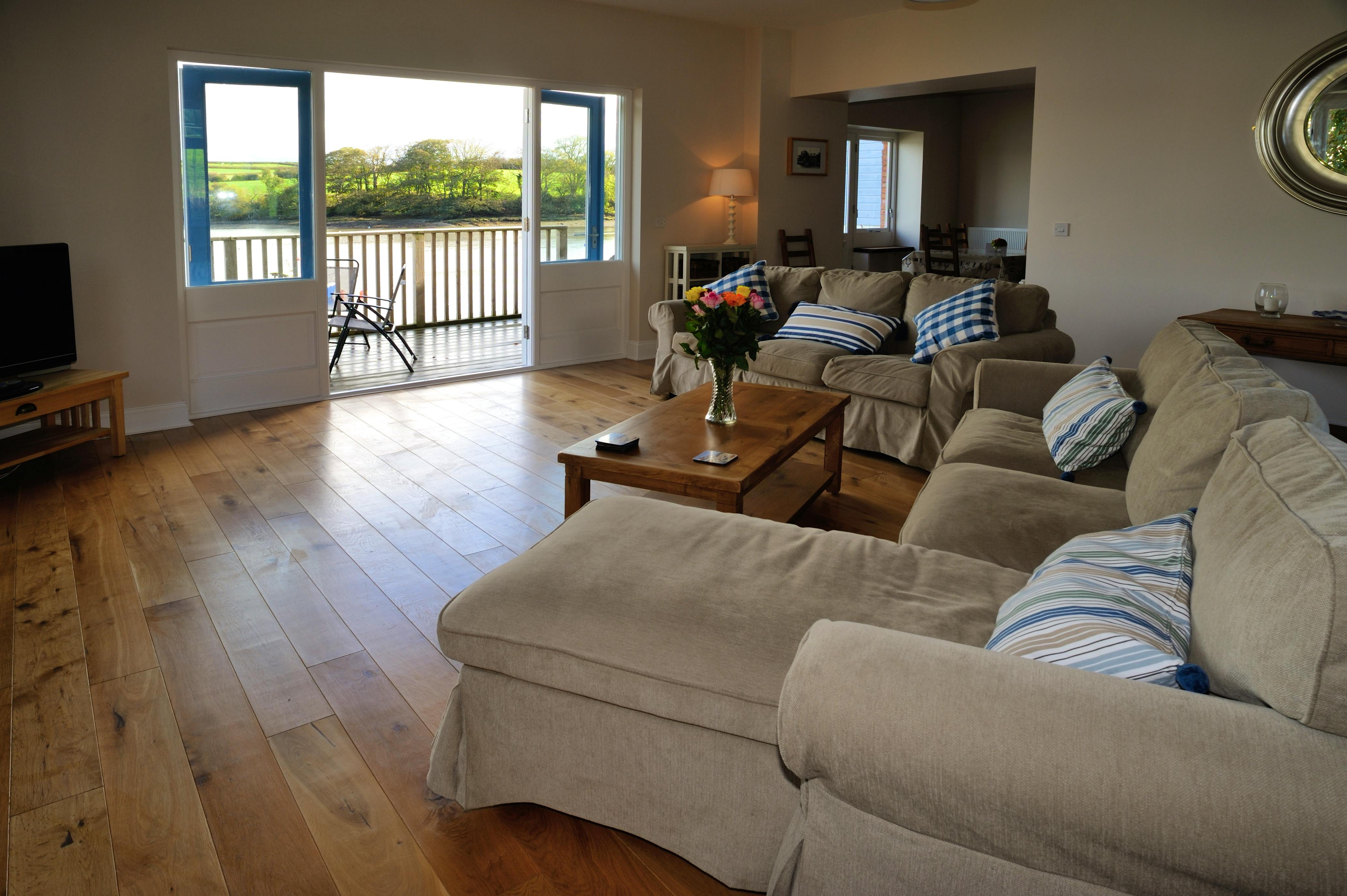 Sitting room with doors to decking overlooking the tidal estuary of the River Teifi