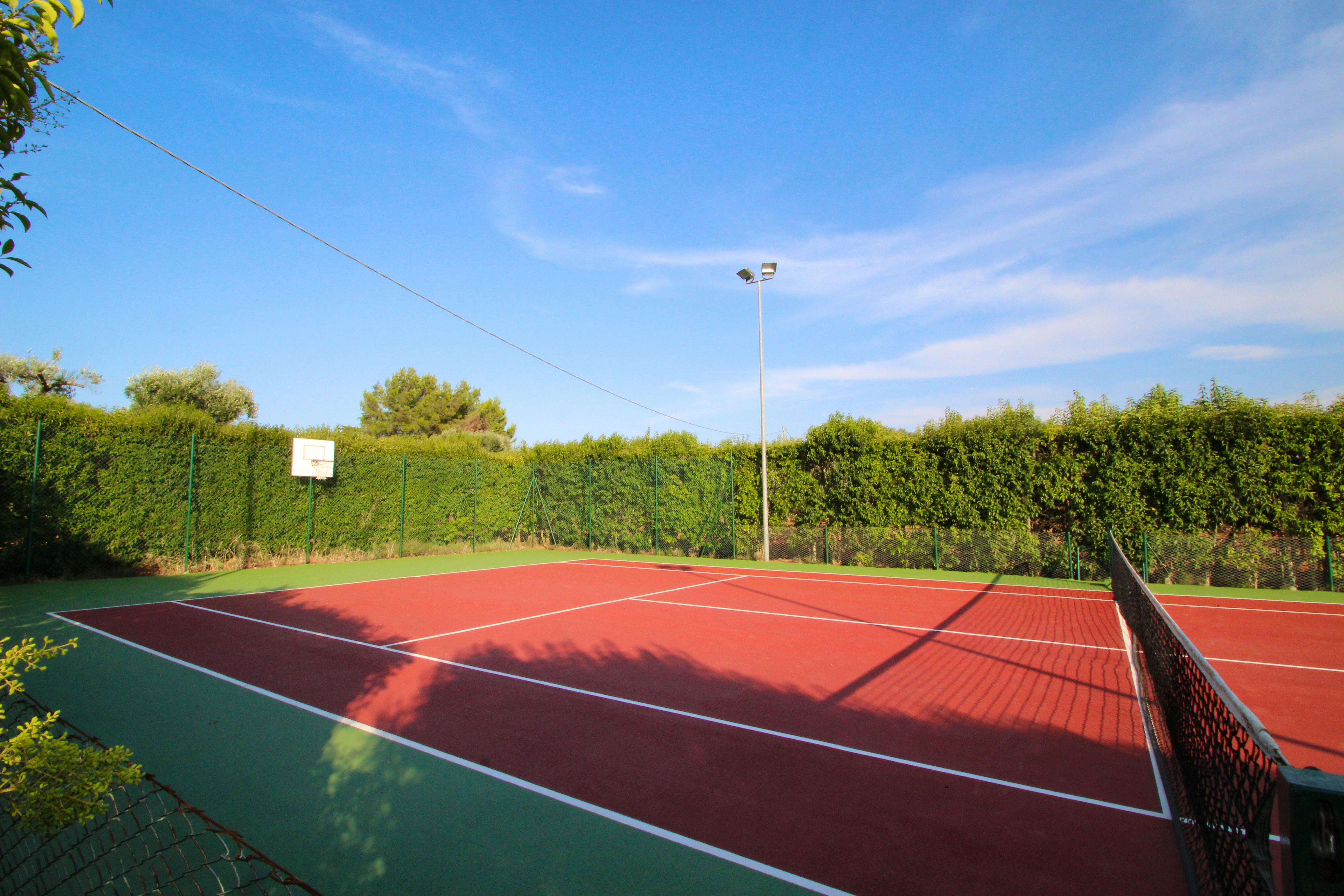 Tennis court with flood lights and basket ball net